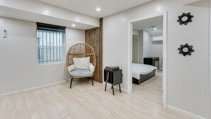 Une chambre à coucher moderne avec un lit, une chaise, une petite table et une fenêtre avec des barreaux.