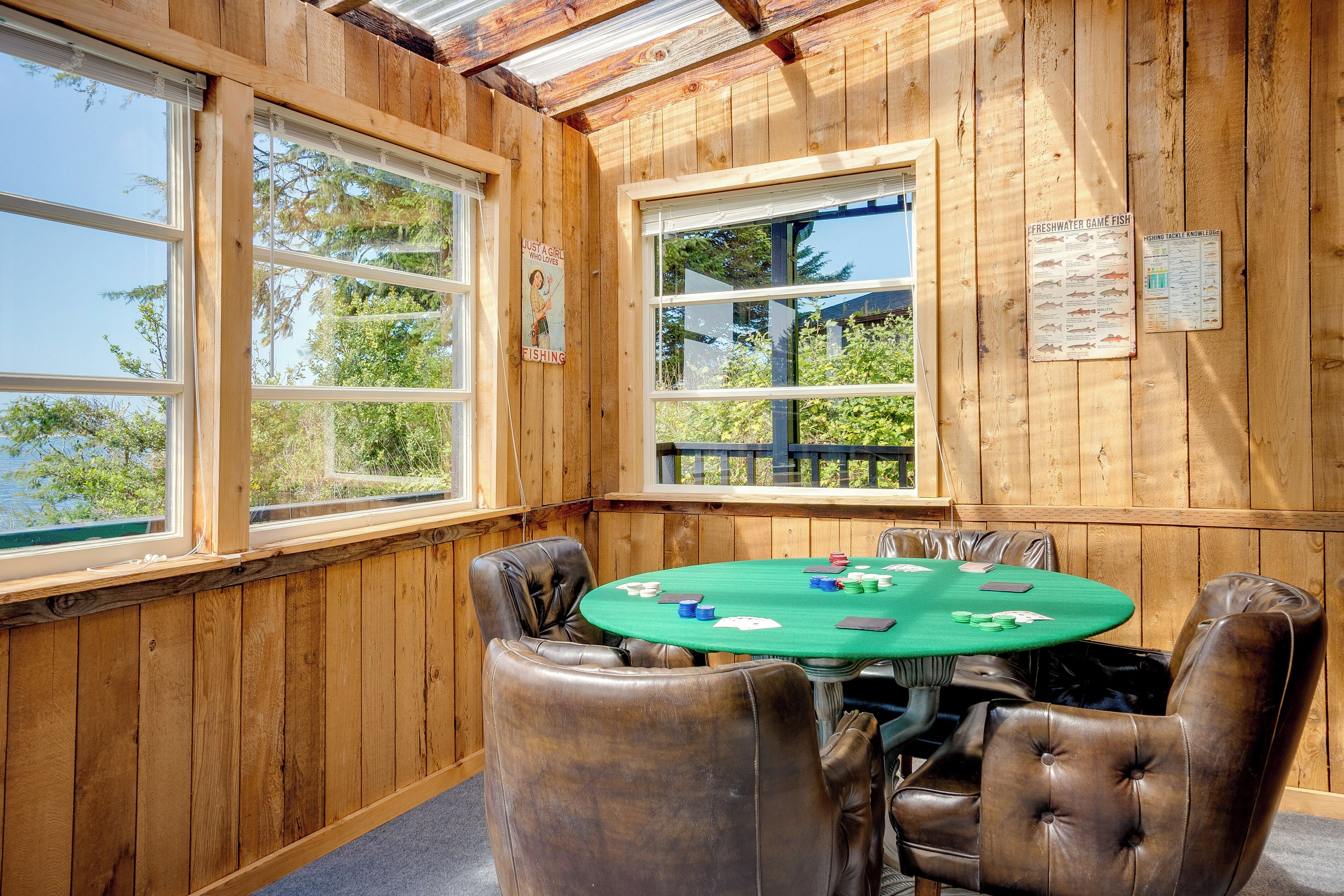 Una habitación de madera con una mesa verde y sillas de cuero, una ventana y un cartel en la pared.