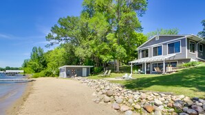 A lakeside property with a house, a dock, and a covered patio area.