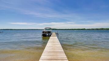A wooden dock extending into a calm lake with a clear sky.