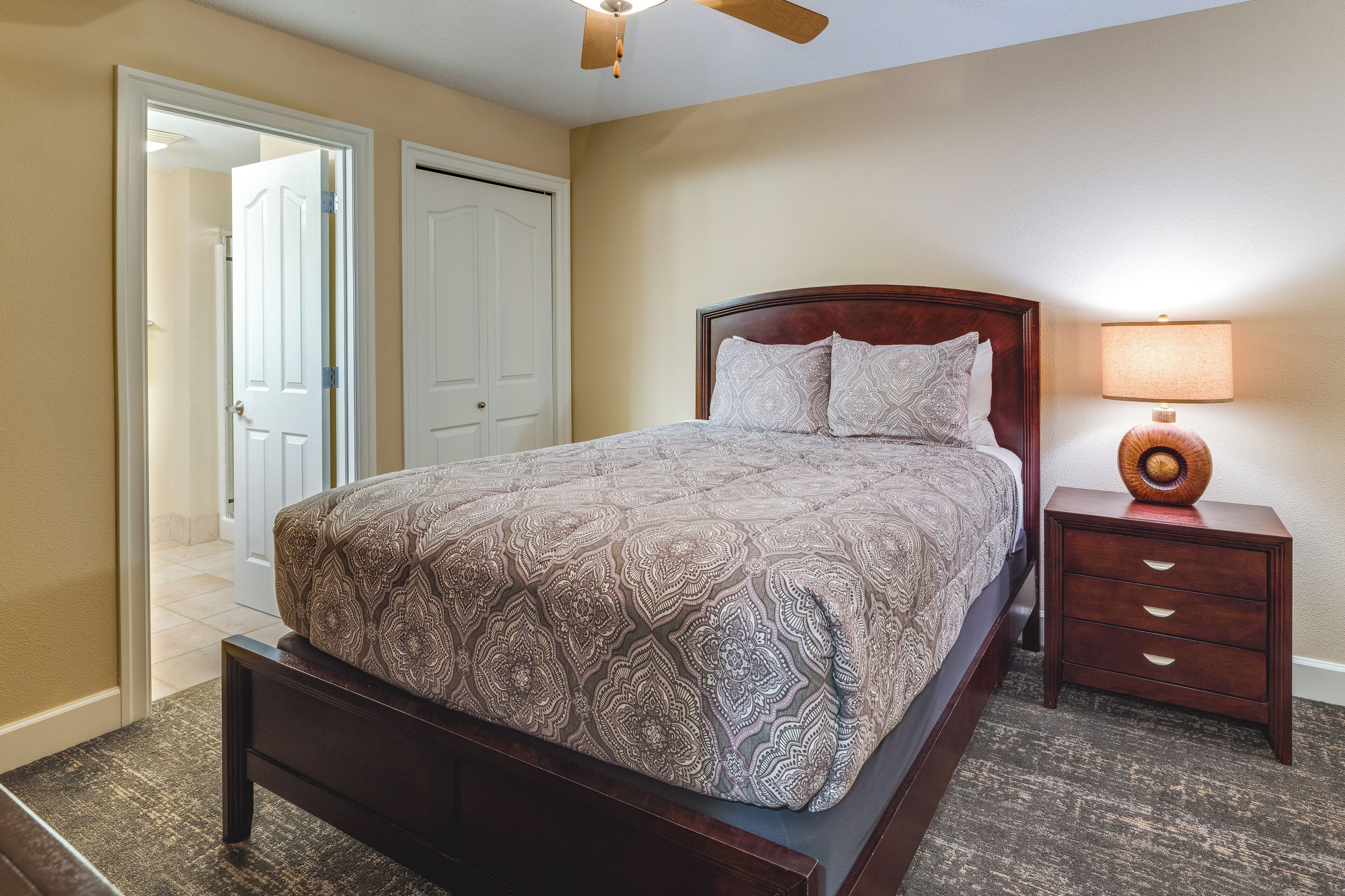 A bedroom with a bed, a nightstand, a lamp, and a ceiling fan.