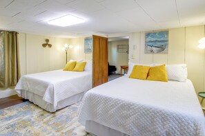 A hotel room with two beds, a wooden door, a painting on the wall, and a small table with a lamp. - Jefferson City Getaway - 3 Mi to Cherokee Lake! (Jefferson City)