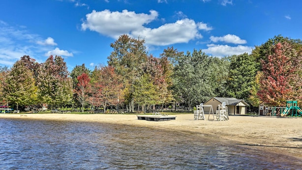 A lakeside park with a sandy beach, a playground, and a small building. - Deck & Screened Porch: Pocono Lake Vacation Rental (Pocono Lake)