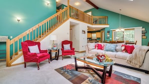 A spacious living room with a staircase, a dining area, and a kitchen. - Deck & Screened Porch: Pocono Lake Vacation Rental (Pocono Lake)