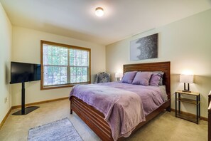 A bedroom with a bed, a TV, a window, and a painting on the wall. - Deck & Screened Porch: Pocono Lake Vacation Rental (Pocono Lake)
