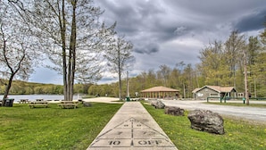 A concrete shuffleboard court with a '10 OFF' marking, picnic tables, and a gazebo in a park setting. - Deck & Screened Porch: Pocono Lake Vacation Rental (Pocono Lake)