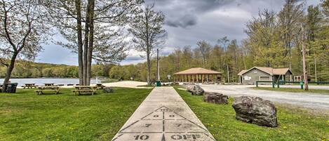 A concrete shuffleboard court with a '10 OFF' marking, picnic tables, and a gazebo in a park setting.