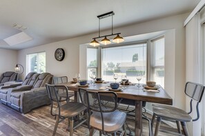 A dining area with a wooden table, metal chairs, and a ceiling light fixture. - Charming Rogue Valley Home in Central Point! (Central Point)
