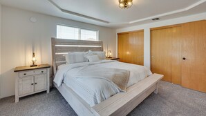 Une chambre à coucher avec un grand lit, une tête de lit en bois, deux tables de chevet avec des lampes et une armoire.