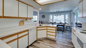 Une cuisine moderne avec des meubles blancs, des éléments décoratifs en bois et un îlot central.