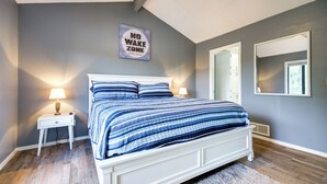 A bedroom with a bed, nightstands, a wall-mounted sign, a mirror, and a ceiling fan. - Waterfront Home w/ Views & Dock in Sunrise Beach! (Sunrise Beach)