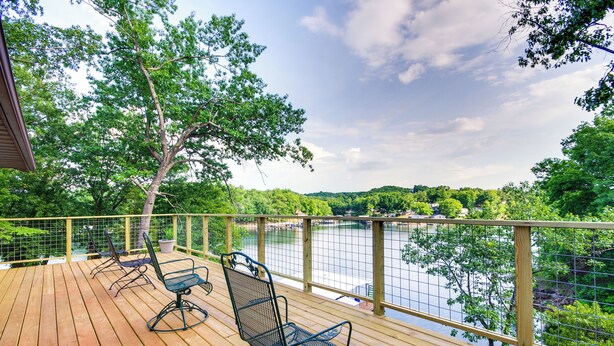 A wooden deck with metal chairs overlooking a lake, surrounded by trees and a wooden railing. - Waterfront Home w/ Views & Dock in Sunrise Beach! (Sunrise Beach)