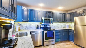 A modern kitchen with dark blue cabinets, stainless steel appliances, and a marble countertop. - Waterfront Home w/ Views & Dock in Sunrise Beach! (Sunrise Beach)