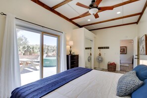 Relax in this serene bedroom with a large bed, ceiling fan, and sliding glass door leading to an outdoor space.