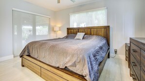 A bedroom with a bed, a ceiling fan, a window, and a nightstand.