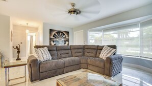A spacious living room with a large sectional sofa, a glass coffee table, and a ceiling fan.