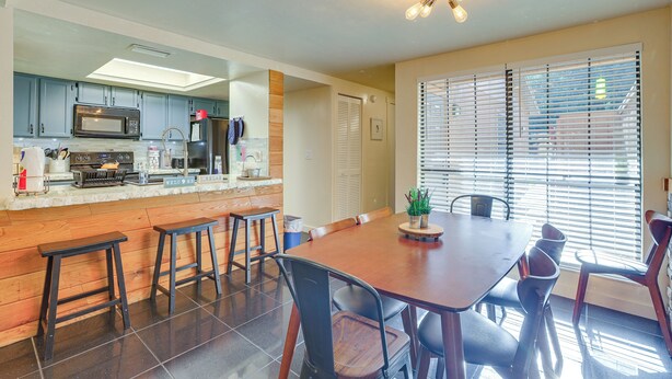 Una cocina moderna con microondas, estufa y barra. Hay una mesa de comedor con sillas y una planta en maceta.