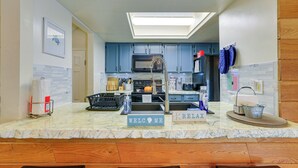 Una cocina con armarios azules, un microondas y un fregadero. Hay letreros que dicen "WELCOME" y "RELAX".