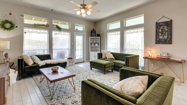 A spacious living room with a green sofa set, a wooden coffee table, and a ceiling fan. - La Porte Home w/ Balconies: Walk to Beach! (La Porte)