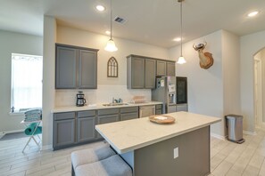 Cozinha moderna com armários cinzas, bancada de mármore e iluminação pendente.