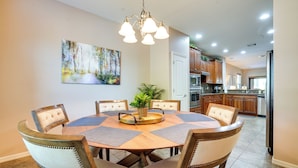 Un coin repas avec une table ronde, six chaises et un lustre.