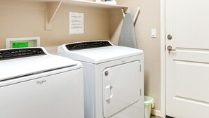 Un espace buanderie équipé de deux lave-linge Whirlpool, d’un étendoir et d’une porte blanche.