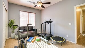 Une salle de sport à domicile équipée de matériel d’exercice, d’un tapis de course, d’un vélo d’appartement et d’un trampoline.