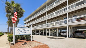 Un hotel de varios pisos con un letrero que dice "SeaCoast Suites" y un estacionamiento con varios coches.