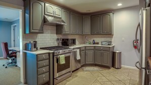 Une cuisine avec des meubles de couleur grise, une cuisinière en acier inoxydable, un four à micro-ondes et une poubelle.