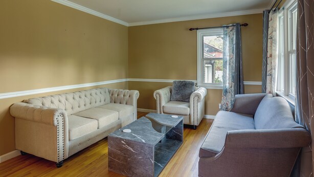 Un salon avec un canapé beige, un canapé gris et une table basse en marbre.