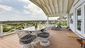 A covered outdoor area with a table and chairs, a wooden deck, and a view of the beach. - Oceanfront Amelia Island Cottage: Deck & Boardwalk (Fernandina Beach)