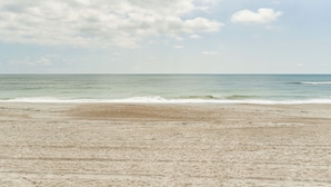 A beach with a sandy shore and calm ocean waves. - Oceanfront Amelia Island Cottage: Deck & Boardwalk (Fernandina Beach)