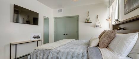 A bedroom with a bed, a ceiling fan, a bedside table, a mirror, and a door.