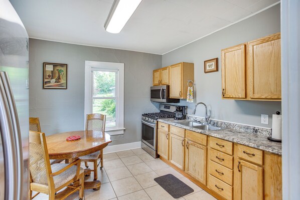 A kitchen with wooden cabinets, a granite countertop, a stove, and a dining table with chairs. - Lakefront Mound Getaway: Near Snowmobiling Trails! (Mound)
