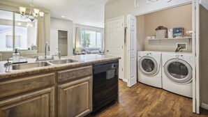 A kitchen with a built-in dishwasher, double sink, and a sign that says "be our guest."
