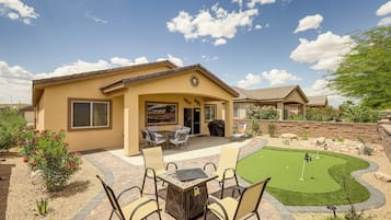 A residential property with a patio, outdoor seating, and a putting green.