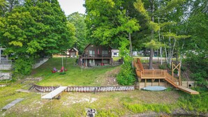 A lakeside cabin with a deck, a small dock, and a grassy yard. - Lakefront Cabin on Secord Lake Sleeps 6 (Alger)