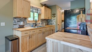 A kitchen with wooden cabinets, a black refrigerator, and a stone backsplash. - Lakefront Cabin on Secord Lake Sleeps 6 (Alger)