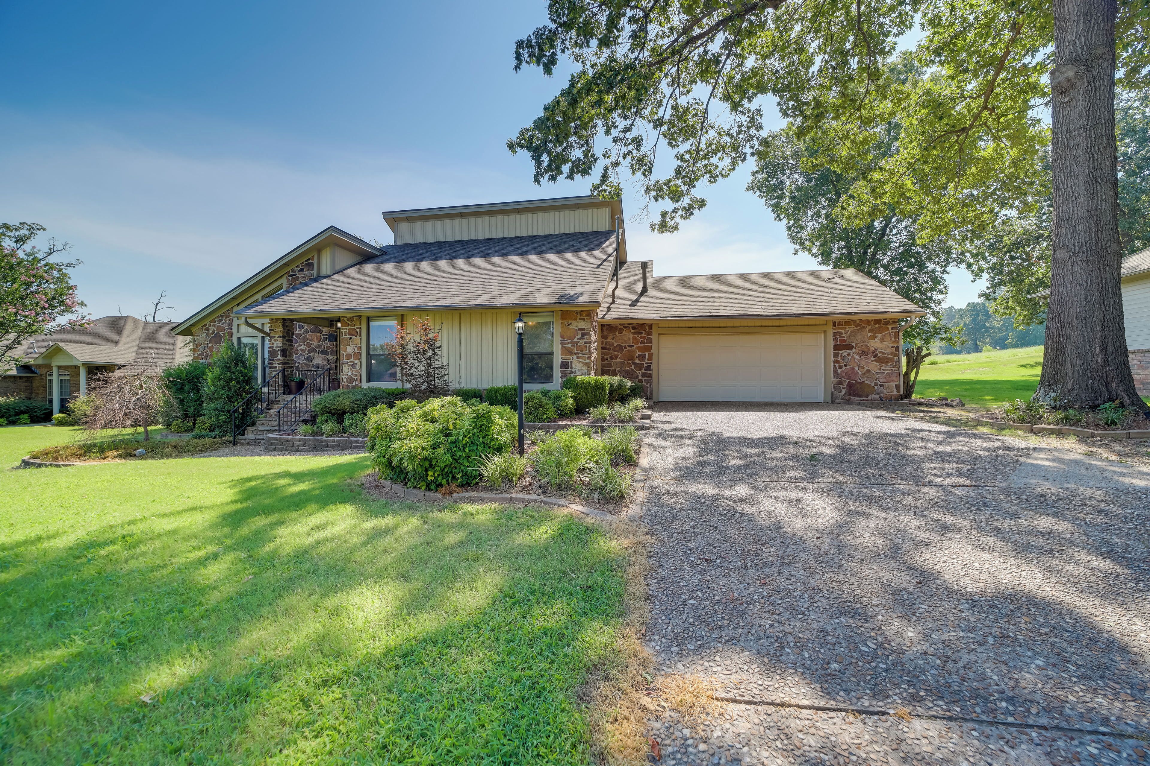 A two-story house with a stone facade, a front porch, and a driveway leading to a garage.