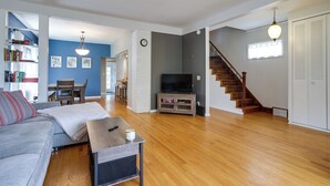 A living room with a sofa, a coffee table, a TV, and a staircase.