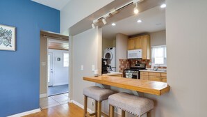 A kitchen with wooden countertops, a microwave, and a stove. There are two stools and a small table.