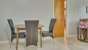 A dining area with a round table and four chairs, a wooden door, and a small table with a basket and flowers. - Cozy Youngstown Apartment w/ Central A/C + Heating (Poland)