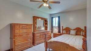 A bedroom with a wooden bed, a dresser, a vanity with a mirror, and a ceiling fan. - Cozy Youngstown Apartment w/ Central A/C + Heating (Poland)