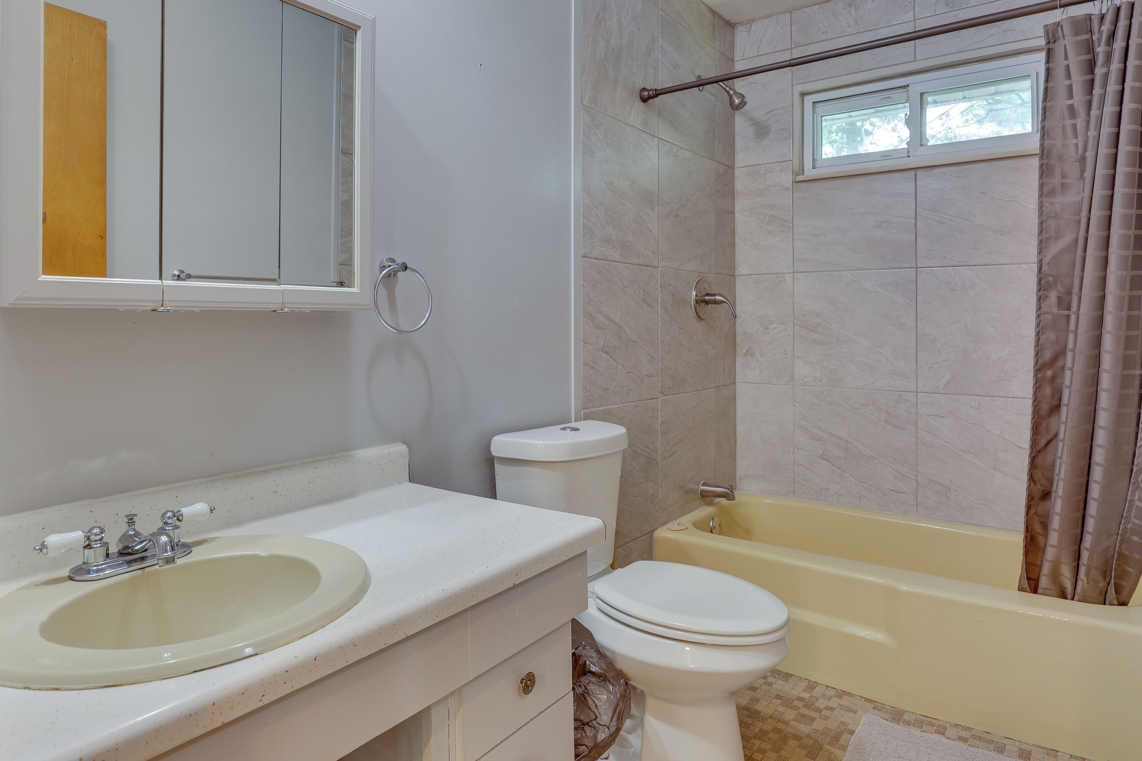 Une salle de bain avec un lavabo, des toilettes, une baignoire et une fenêtre.