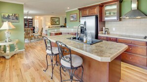 A kitchen with a large island, wooden cabinets, and a stainless steel refrigerator. - Hendersonville Retreat w/ Mtn Views & Deck! (Hendersonville)