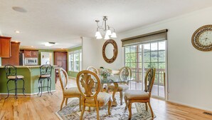 A dining area with a glass table surrounded by ornate chairs, a chandelier, and a large mirror on the wall. - Hendersonville Retreat w/ Mtn Views & Deck! (Hendersonville)