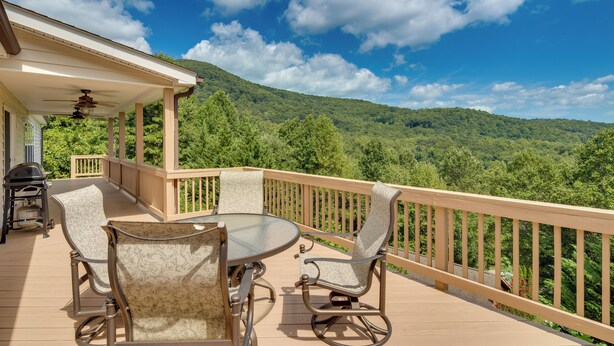 A covered outdoor deck with a table and chairs, overlooking a forested hillside. - Hendersonville Retreat w/ Mtn Views & Deck! (Hendersonville)