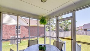 A covered patio with a round table, chairs, and a hanging plant. - Roomy Fayetteville Home Rental w/ Screened Porch! (Fayetteville)