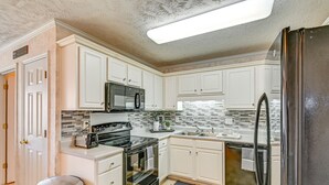 A kitchen with white cabinets, a black refrigerator, a microwave, a stove, and a dishwasher. - Roomy Fayetteville Home Rental w/ Screened Porch! (Fayetteville)