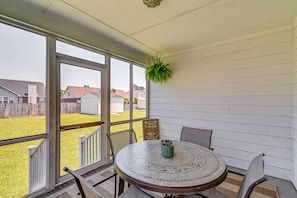 A covered patio with a round table, chairs, and a hanging plant. - Roomy Fayetteville Home Rental w/ Screened Porch! (Fayetteville)